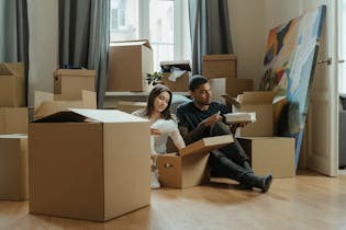 A Boy and Girl Sitting on Brown Cardboard Box