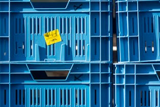 Close-up of stacked blue plastic crates with a quality control label.
