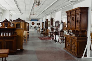 A spacious showroom filled with various antique wooden furniture pieces on display.