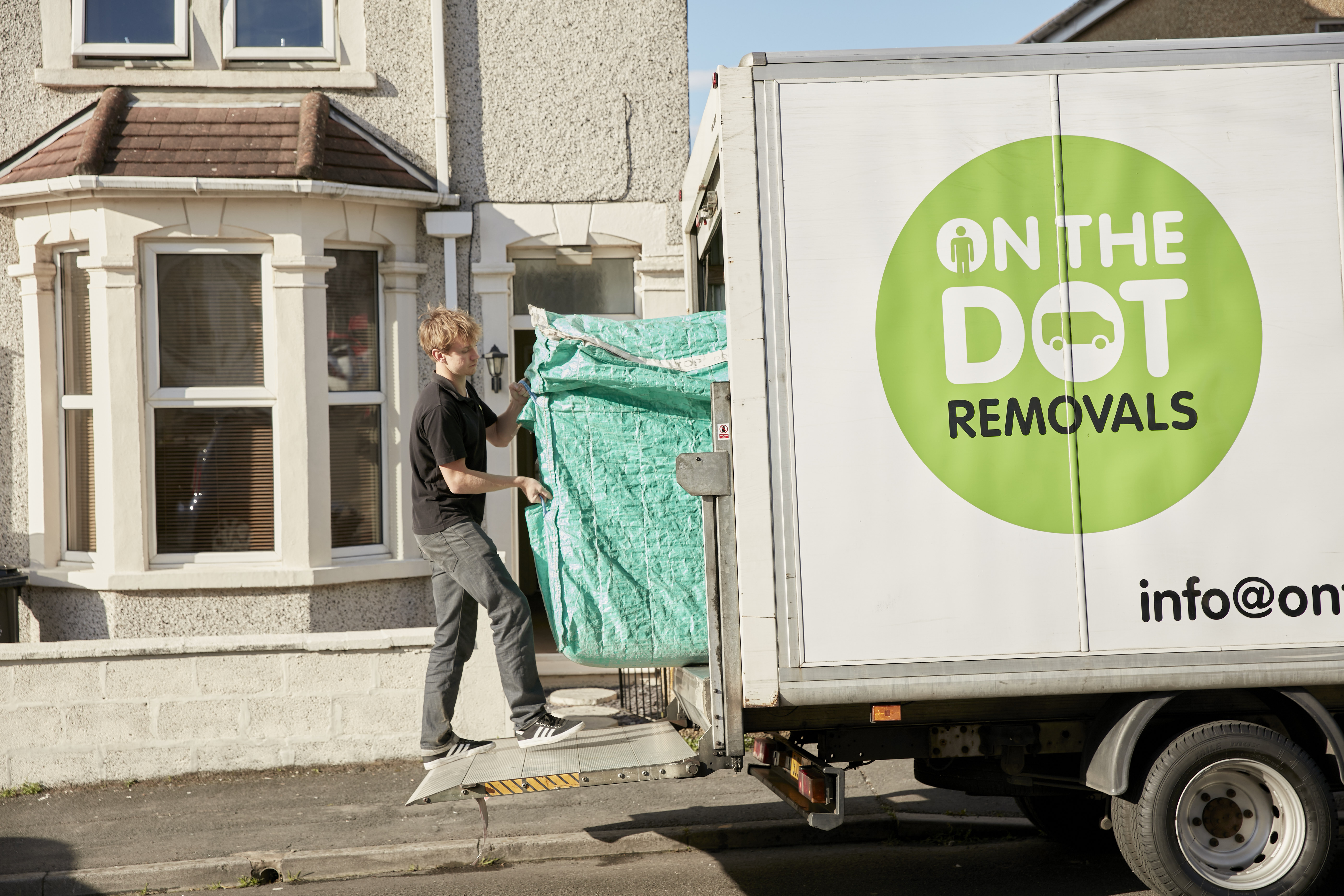 On The Dot Removals mover loading a wrapped wardrobe into a removal van outside a Bristol house