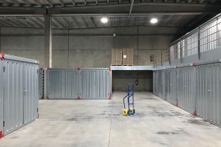 Modern warehouse interior with metal storage units and a blue hand truck on the concrete floor.